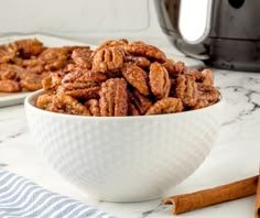 two white bowls filled with candies sitting on top of a counter next to cinnamon sticks