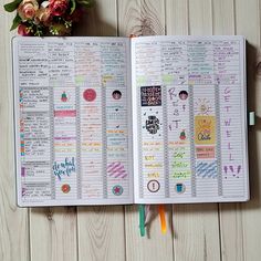 an open planner book with stickers on it next to a bouquet of flowers and pencils