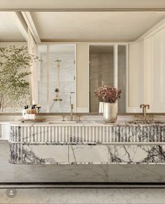 an elegant bathroom with marble counter tops and gold faucets, along with white cabinets