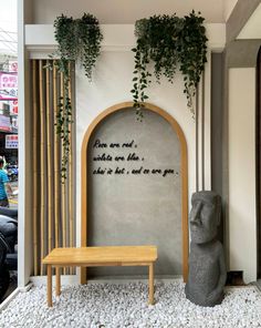 a bench sitting in front of a wall with writing on it and plants growing over the top