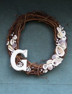 the letter c is made out of seashells on a grapevined wreath