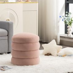 a living room with white rugs and pink ottomans on the floor in front of a window