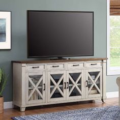 a flat screen tv mounted on top of a wooden entertainment center in a living room