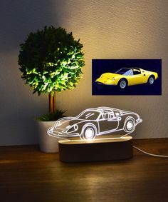 a yellow sports car sitting on top of a table next to a potted plant