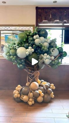 a large tree made out of balloons in a room with tile flooring and windows