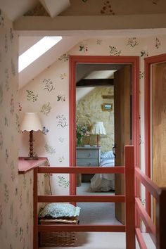 an open door leading to a bedroom with pink walls and floral wallpaper on the walls