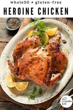 a whole chicken on a plate with lemons and parsley