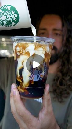 a person holding up a starbucks cup filled with liquid