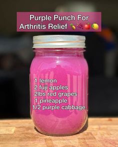 a jar filled with pink colored liquid sitting on top of a wooden table next to a sign that says purple punch for arthriis relief