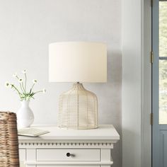 a white lamp sitting on top of a table next to a vase with flowers in it