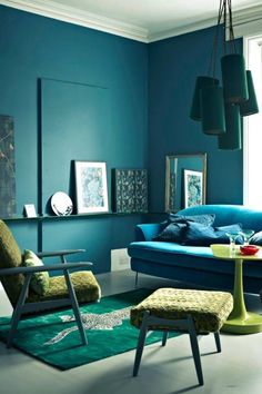 a living room with blue walls and green furniture in the corner, along with pictures on the wall