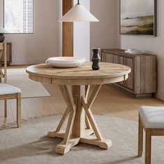 a wooden table with two chairs and a lamp on it in a living room next to a window