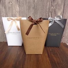 three thank you bags with brown ribbon and bow on the front, one in black, one in white