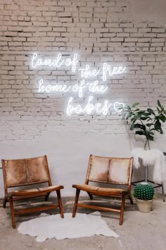 two chairs sitting next to each other in front of a brick wall with neon lights