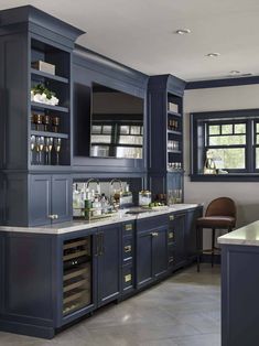 a kitchen with dark blue cabinets and marble counter tops, along with an island in the middle