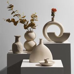 three white vases sitting on top of each other next to each other with flowers in them