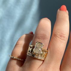 a woman's hand with two gold rings on it and an engagement ring in the middle