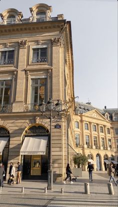 people are walking around in front of a building with many windows and balconies