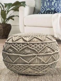 a large woven basket sitting on top of a rug in front of a white couch