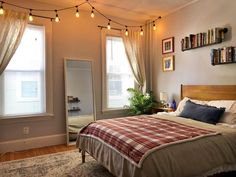 a bed room with a neatly made bed and lots of lights hanging from the ceiling