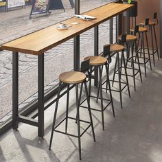 a row of bar stools sitting in front of a window with an empty plate on it