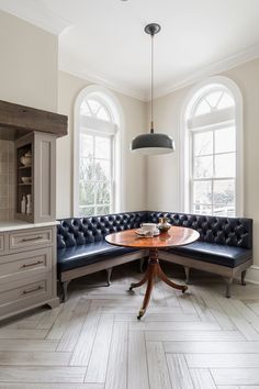 a corner table sits in the middle of a room with two windows and a bench