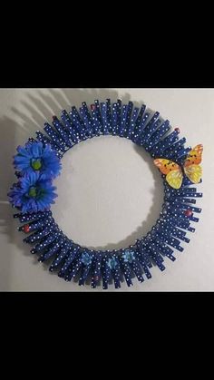 a blue beaded wreath with flowers and butterflies hanging on the wall next to it