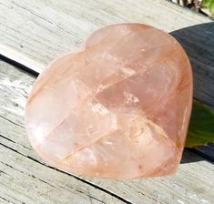 a large pink rock sitting on top of a wooden table next to a green leaf