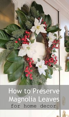 a christmas wreath with white flowers and greenery hanging on the front door to welcome guests