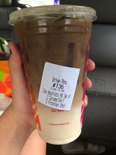 a person holding up a plastic cup filled with coffee