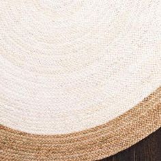 a close up view of a white and brown rug on a wooden floor with wood floors