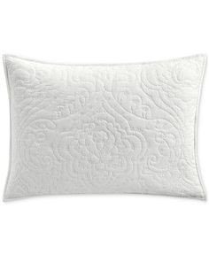 the white quilted pillow is made from cotton and has an intricate design on it