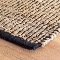 a black and beige rug on top of a wooden floor