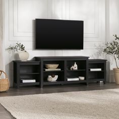 a flat screen tv sitting on top of a black entertainment center next to a potted plant