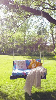 a blue and white couch sitting on top of a swing in the middle of a field