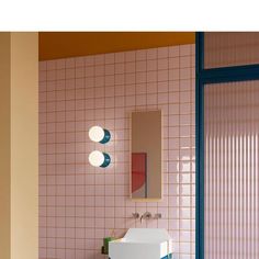 a bathroom with pink and blue tiles on the walls, sink and mirror in it