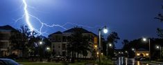 a lightning bolt is seen in the sky over some buildings and cars on a street