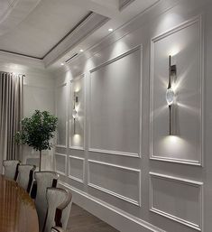 an elegant dining room with white walls and wood flooring is lit by recessed lighting