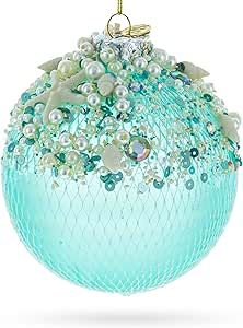 a glass ball ornament with pearls and leaves