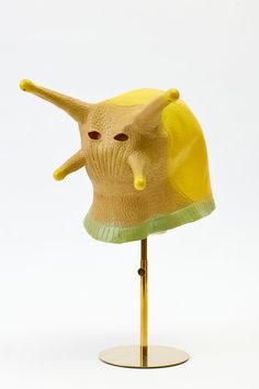 a yellow and green hat on top of a wooden stand