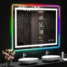 a bathroom with two sinks and a large mirror on the wall above it that is lit up by colorful lights