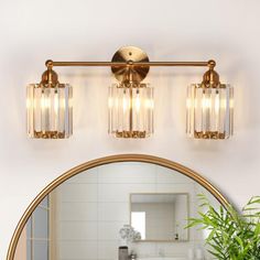 a bathroom vanity light with three lights on it and a mirror over the sink in front of it