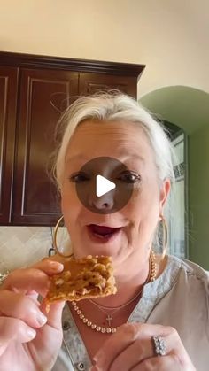 an older woman holding up a piece of food to her face and making a funny face