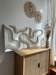 a wooden cabinet sitting in front of a window next to a vase with flowers on it