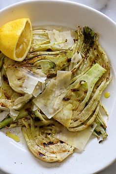 a white plate topped with artichoke and lemon wedges