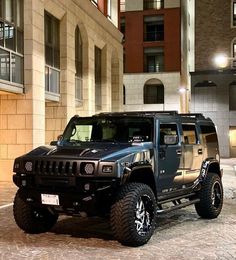 a hummer truck parked on the side of a street in front of a building