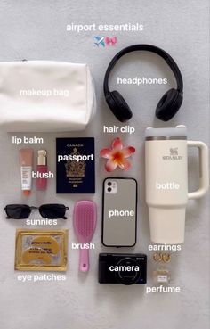 the contents of a travel bag laid out on top of a white surface with headphones and other items