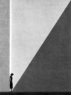 a person standing in front of a tall building with a shadow on it's wall