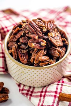 a hand is picking up some pecans from a bowl