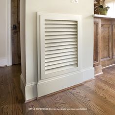 a white radiator in a room with wood flooring and wooden paneling